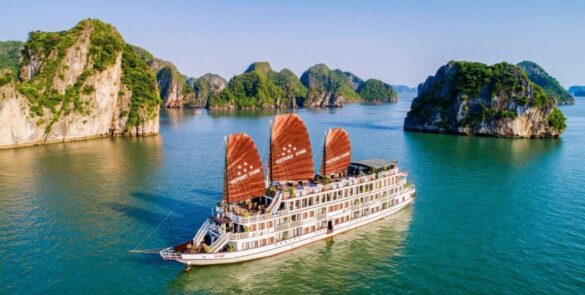 Cruise boat sailing in Halong Bay with limestone karsts and clear waters.