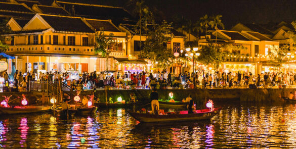 The colorful streets of Hoi An during the Lantern Festival, with vibrant lanterns reflecting on the river.