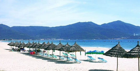 A view of the clear waters and sandy shores of My Khe Beach in Da Nang, with beachgoers enjoying the scenery.
