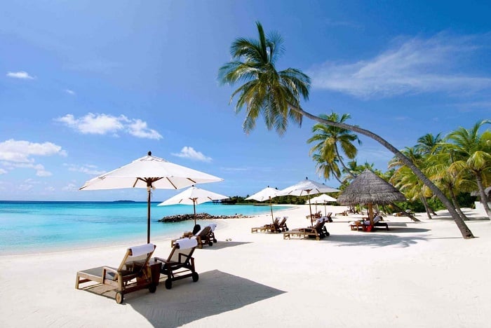 Tourists relaxing on the sandy beaches of Nha Trang with clear blue skies and calm sea waters.